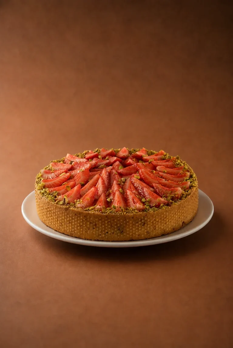 tarta frutilla pistachos lateral sobre fondo marrón cálido